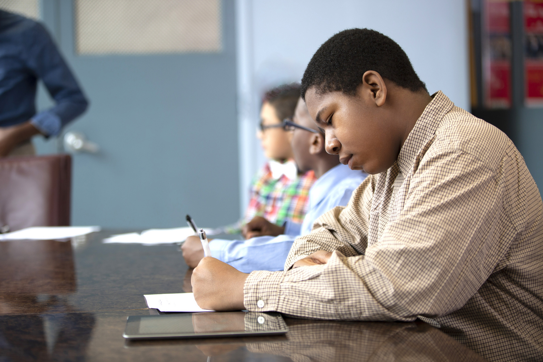 Young Black Boy Sitting in Class Jotting down Important Notes